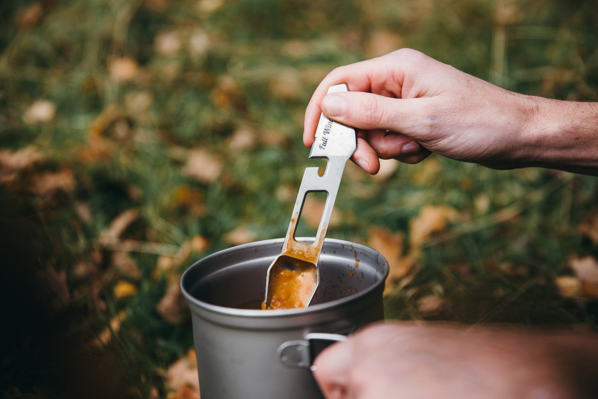 soup in camping mug being stirred with the muncher titanium camping multi utensil
