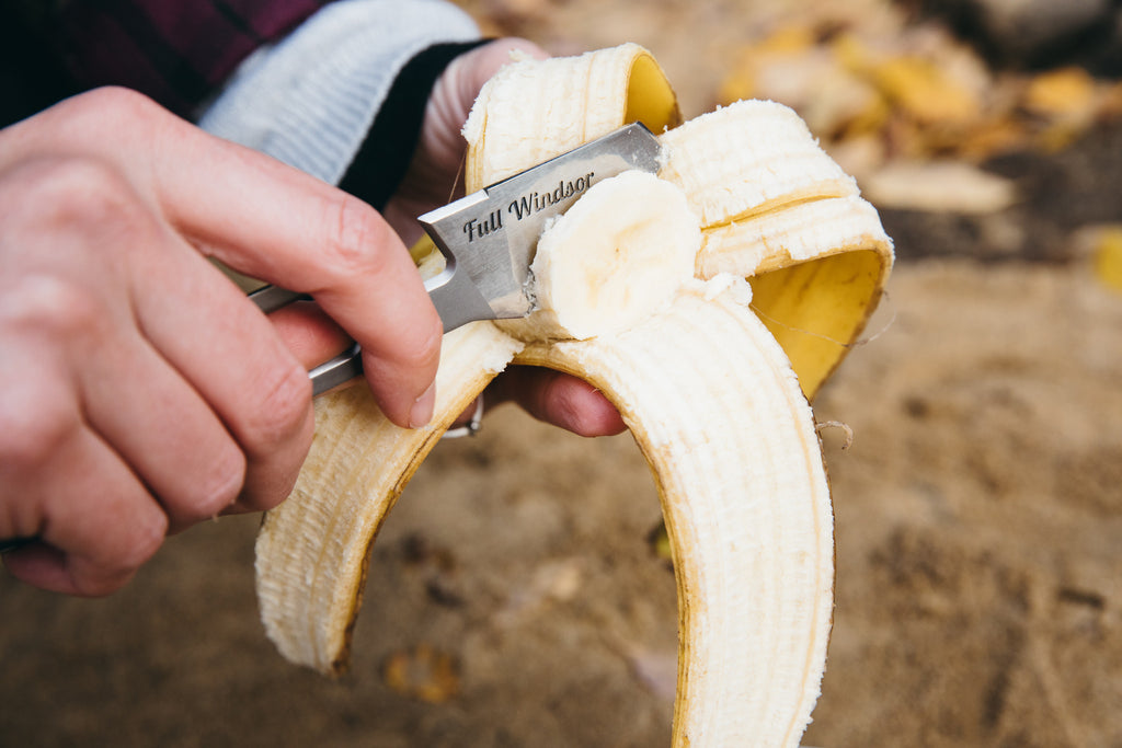 banana being cut with serrated knife of the muncher titanium camping multi utensil
