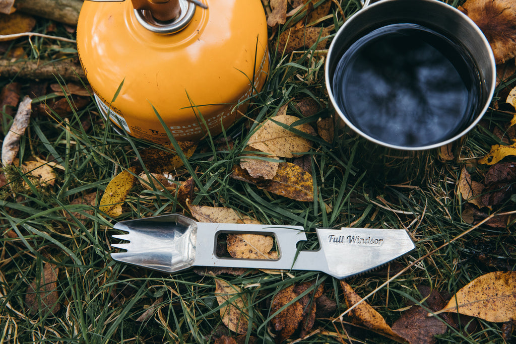 The muncher titanium camping multi utensil next to coffee cup and gas stove