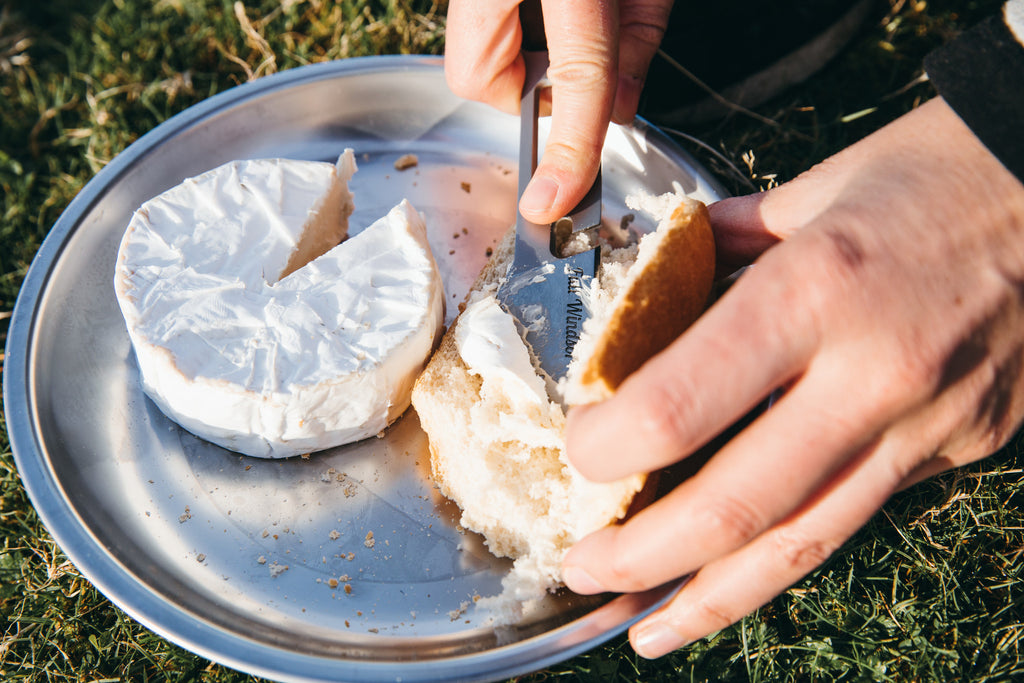 camabert cheese being spread onto bread using the muncher titanium camping multi utensil